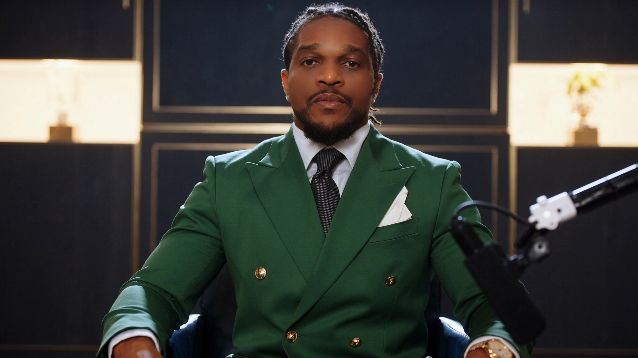 rev-benton-opene-luxington-performance in a green suit sitting in a studio setting